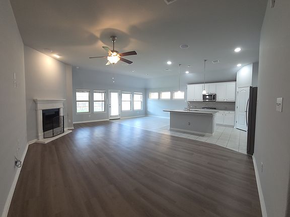 Living room featuring recessed lighting, luxury vinyl plank floors, a ceiling fan, and a glass covered fireplace