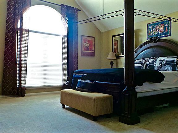 Master bedroom with high ceilings, huge window and ceiling fan.
