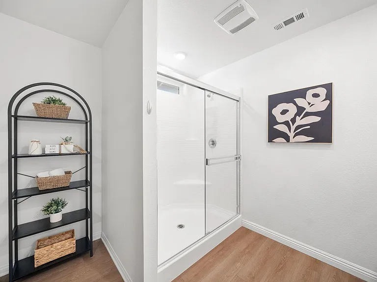 Bathroom features a walk-in shower with glass doors and ample open shelving for towels and toiletries.