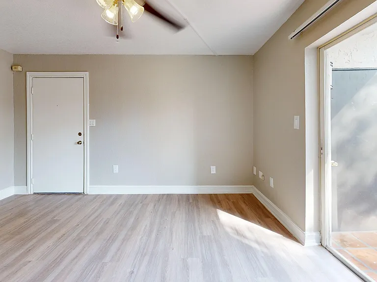 Experience modern elegance with this sunlit living room, featuring sleek flooring and easy outdoor access.