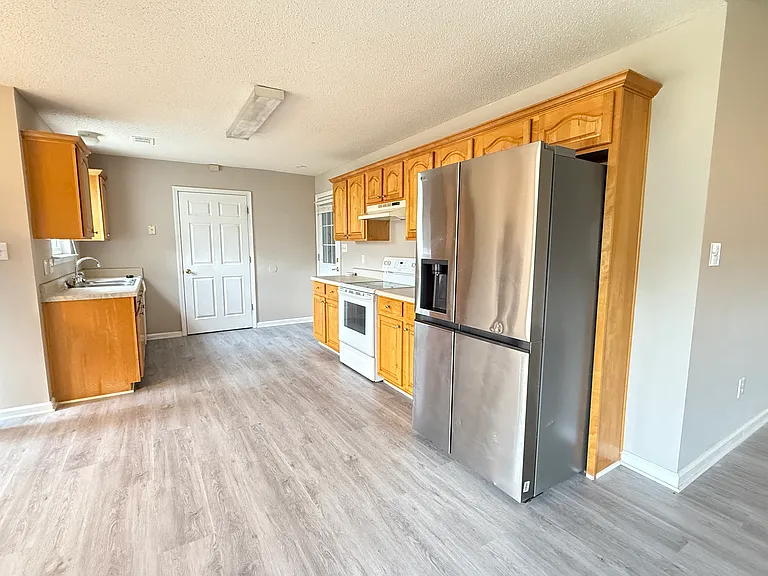Fully equipped kitchen featuring abundant wooden cabinetry and a premium stainless steel refrigerator.