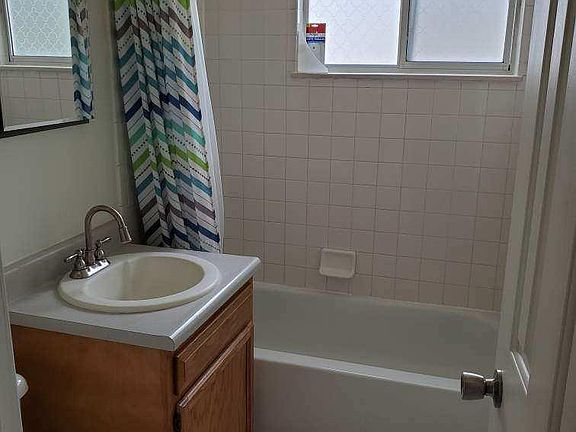 Clean fresh bathroom with tile on tub walls and floor. Lots of mirrors.