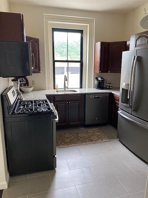 View of Kitchen with Stainless Steel appliances; gas stove, microwave, dish washer, and large fridge.