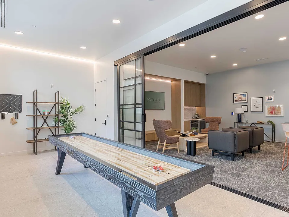 Relax, connect, or challenge friends in a modern resident lounge featuring shuffleboard, conversational seating, coworking areas, and entertainment spaces.