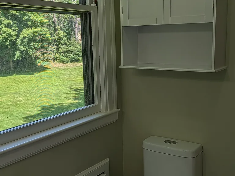 Bathroom looks onto expansive private yard with mature trees.
