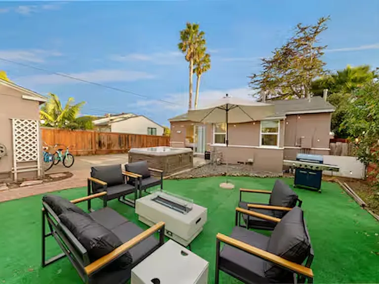 Enjoy the private outdoor space featuring a spacious hot tub that seats 6_8 guests and a cozy fire pit, perfect for relaxing after a beach day. The area also includes a barbecue grill and lawn games, ideal for outdoor dining and fun.
