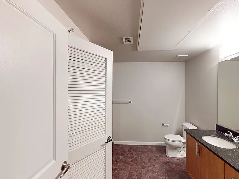 Apartment bathroom with large soaking tub and wood-style flooring.