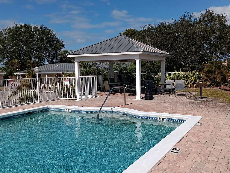 Resort-style outdoor pool area with a shaded pavilion, seating, and fenced deckideal for relaxing or hosting friends.