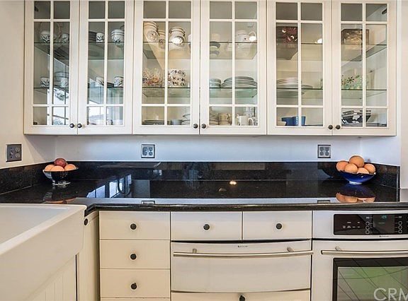 Glass front cabinets with glass shelves, warming drawer, built-in oven, farm sink and beautiful gran