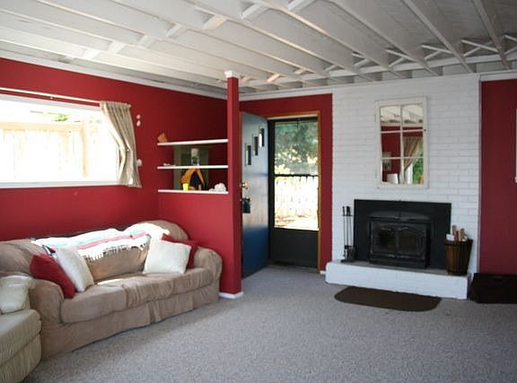 The living room features a wood burning fireplace and a beamed ceiling.