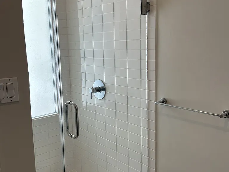 Step-in shower with frameless glass door in full bathroom