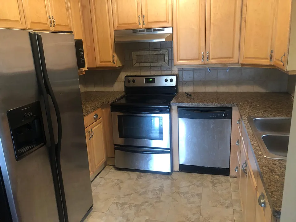 Kitchen with undercabinet lighting. Microwave is hiding behind the fridge. Fridge has water and ice dispenser. Two sink basin.