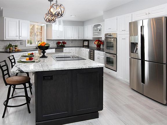Recently renovated (2018) kitchen has large Romanix granite island with downdraft cooktop, under counter microwave and loads of storage in the newly installed, contrasting island. Beveled subway tile backsplash enhances the dramatic honed black granite co
