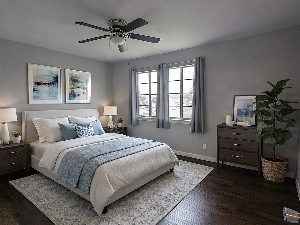 Spacious bedroom with rich dark flooring, ceiling fan, and natural light, creating a comfortable retreat with a clean modern feel.
