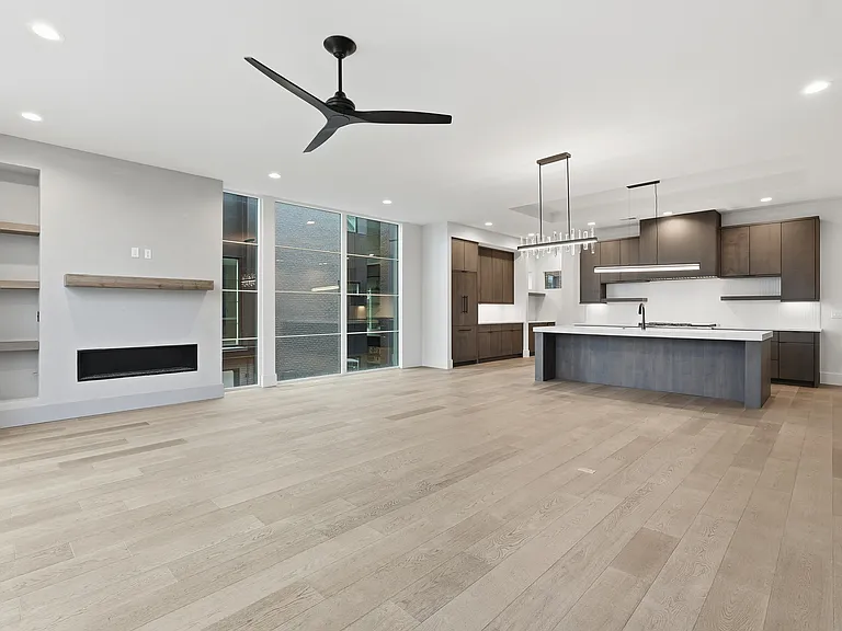 Light- filled living space with contemporary fireplace, designer lighting, and a large kitchen island.