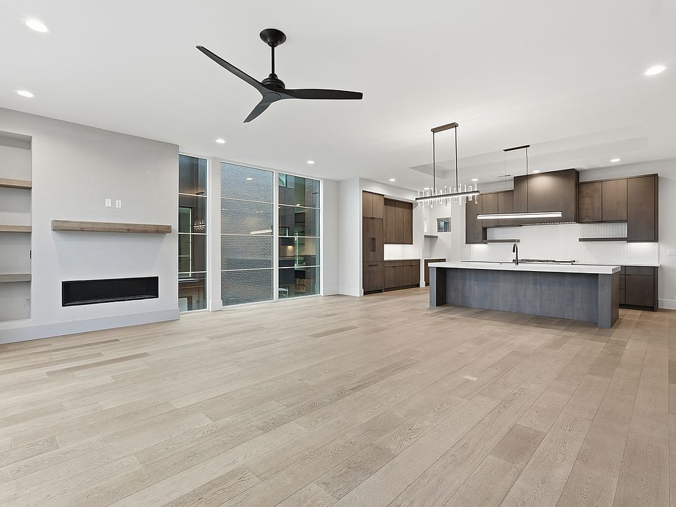 Light- filled living space with contemporary fireplace, designer lighting, and a large kitchen island.