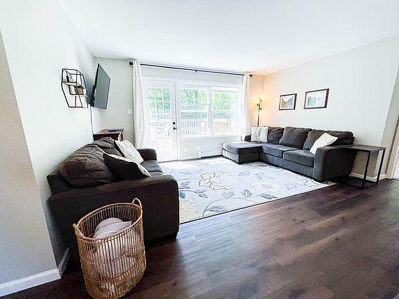 Bright and sunny living room opens up to back deck and wooded backyard