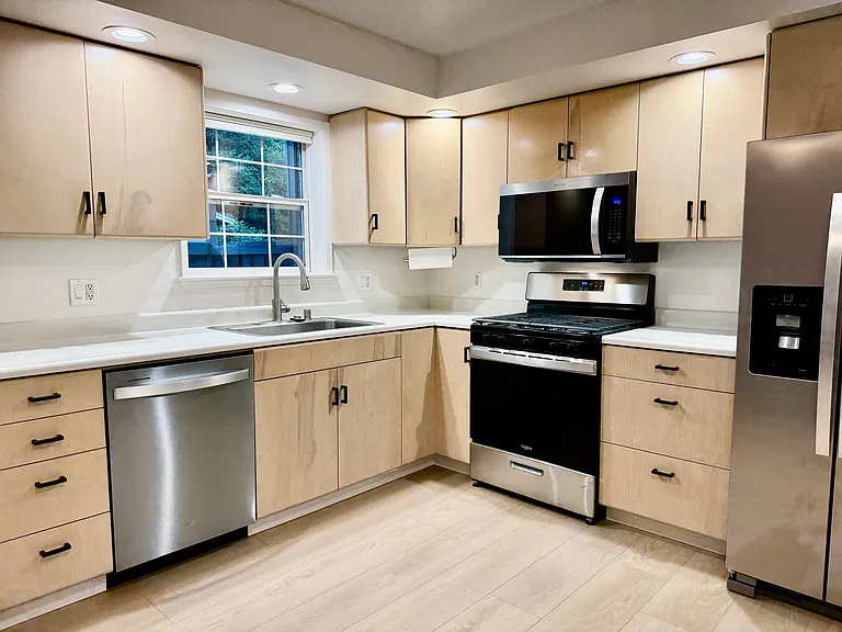 Kitchen with all new appliances. Combines with living room. Multiple windows look out onto front courtyard. New light-filtering window shades.