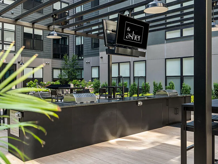Central courtyard featuring lounge seating, bar area, outdoor tv's, and grills