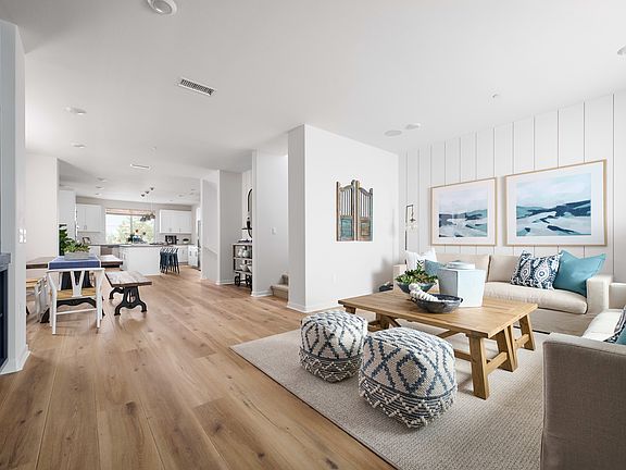 A bright and airy open-concept living space with a cozy seating area, wooden dining table, and a gli