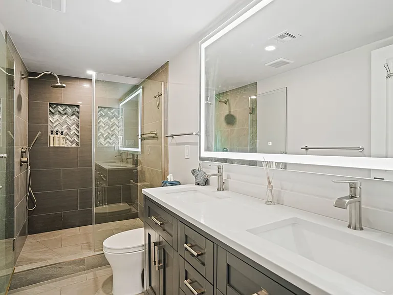 Fully renovated primary bathroom featuring a sophisticated lighted mirror, an indulgent rainfall shower, and premium modern finishes