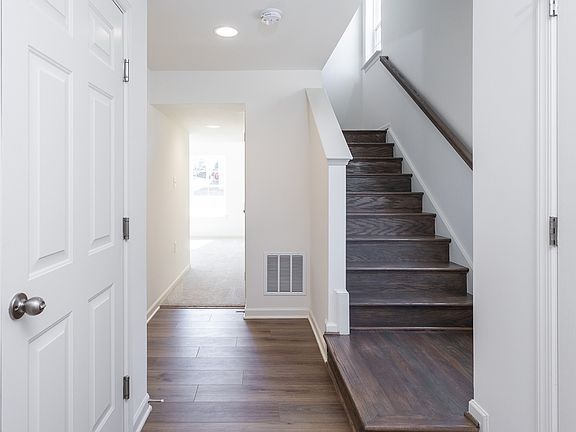 Entry with wood floors and wood stairs in a DRB Homes York II Garage plan at the Archer s Rock commu