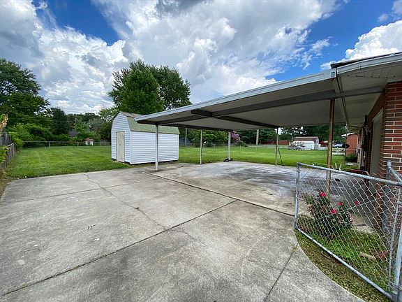 Huge fenced in backyard with a storage shed, carport, and garage access.
