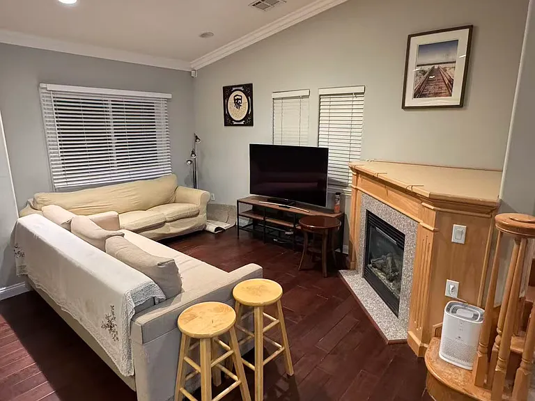 Bright, sunlit living area anchoring the home with architectural vaulted ceilings, rich hardwood flooring, and a gas fireplace.