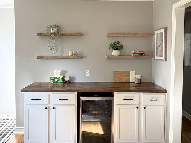 Living room dry bar with extra storage space and a mini fridge.