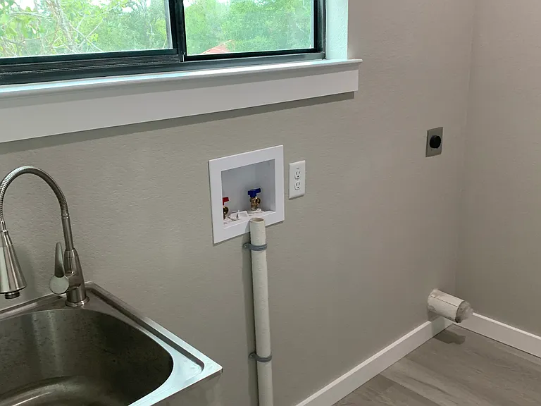 Wash room with wash sink and washer/dryer connections.