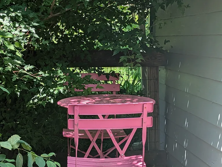 Hot-pink cafe table and two chairs in deck hide-away spot.