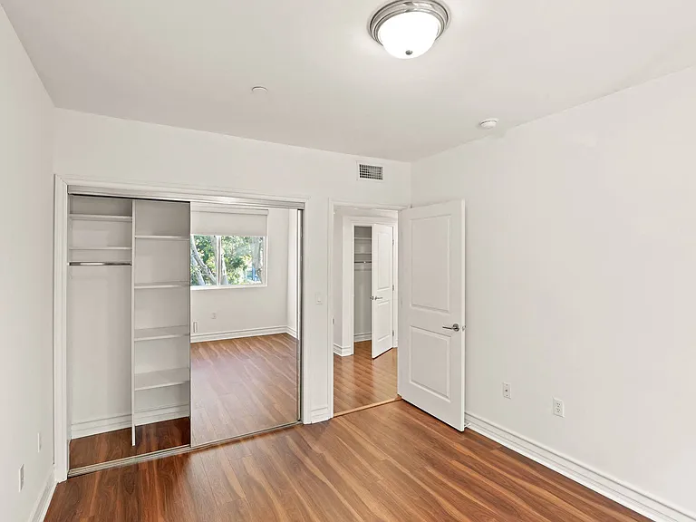 Bedroom with Vinyl Flooring and Mirrored Closet with Built-In Organizers