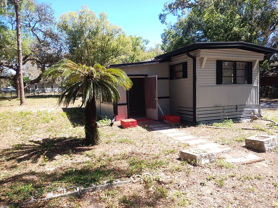 Photo showing an added-on 2 bedrooms and bathroom on the left with the open door. The larger building attached has a large kitchen, living room, 2 bedrooms, a bathroom and large laundry room