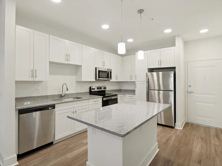 Modern kitchen with sleek white cabinets, stainless steel appliances, and a chic granite island, perfect for culinary enthusiasts.