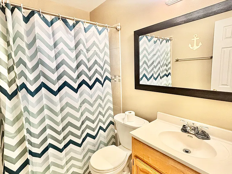 Full bathroom with tub/shower combo, tile flooring, and a wide vanity with mirror and ample under-sink storage.