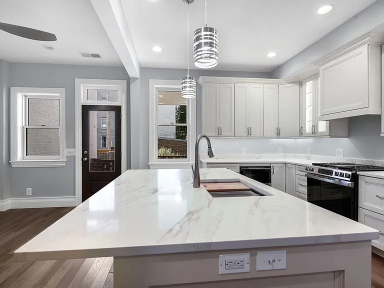close up of Quartz counter top island with overhang for bar stool dining, or homework/work area with receptacles and light switches on side of island