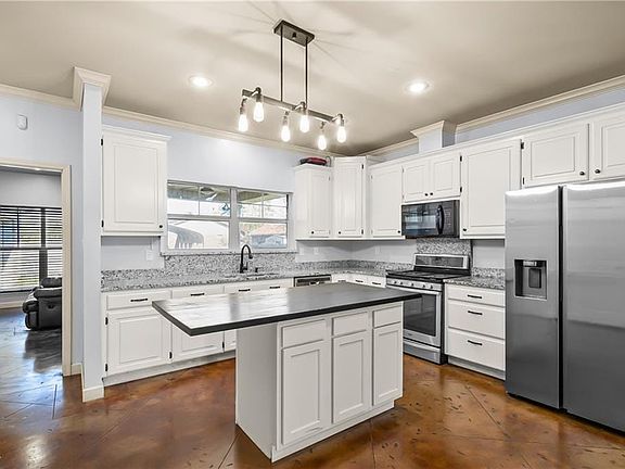 Kitchen featuring appliances with stainless steel finishes, white cabinetry, and decorative light fixtures