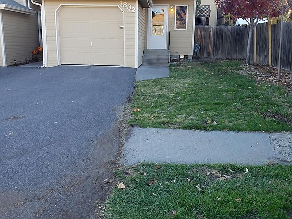 Front view of townhouse with garage and extra off street parking next to front yard.
