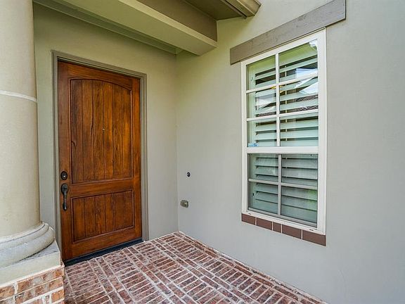 Lovely covered porch with brick flooring and rustic door welcomes our guests