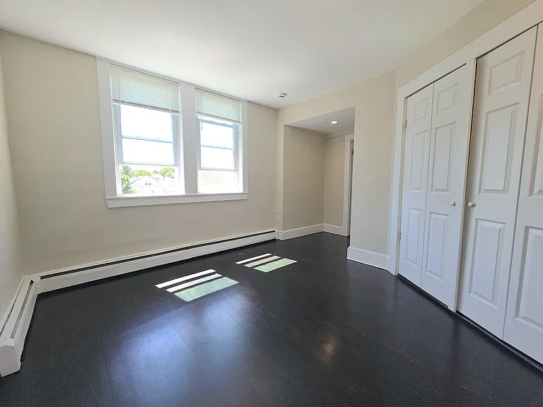 bedroom off kitchen with walk in closet and two windows