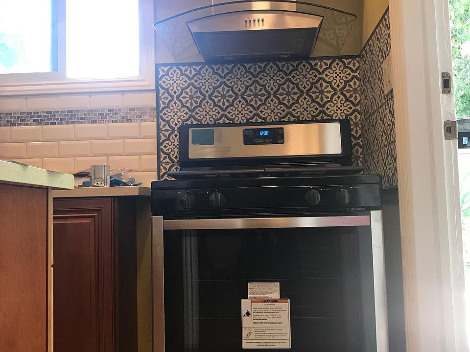Just inside entry door showing new stove, range hood, tile backsplash