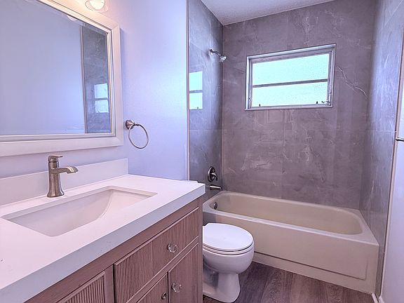 Upscale and updated Hall Bath with solid wood vanity, quartz countertop, brushed nickel faucets, and 32" porcelain tiles