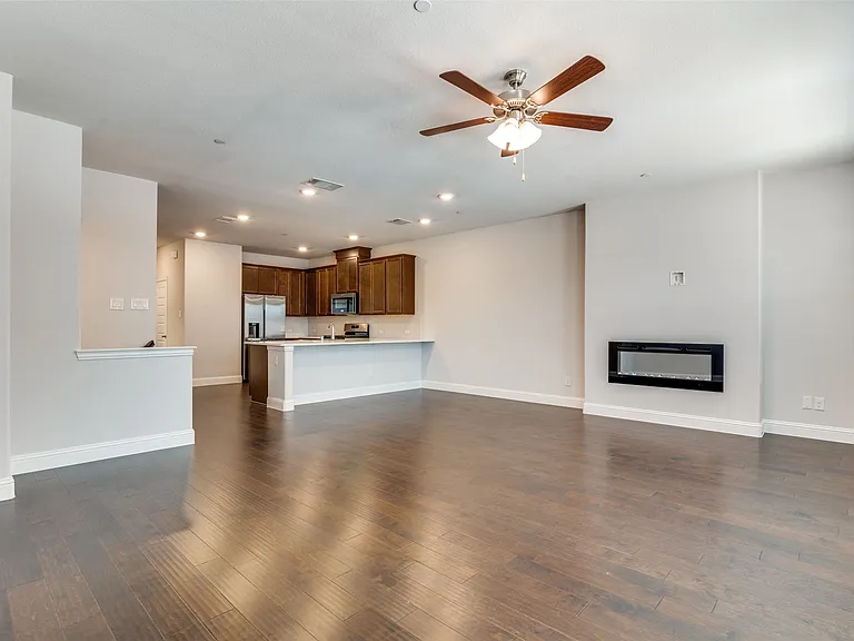 Spacious living area featuring wood-finish flooring, a ceiling fan, and recessed lighting