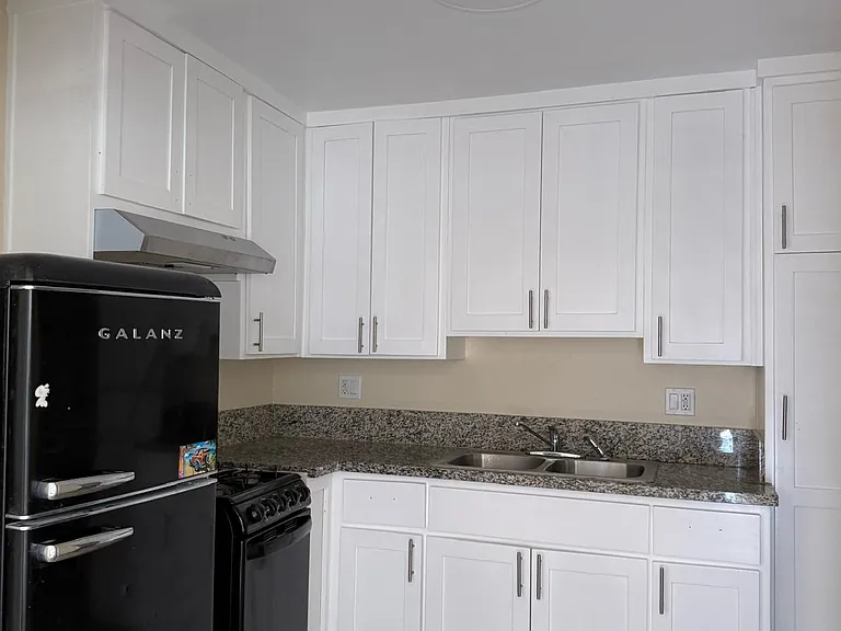 The kitchen has a granite countertop, ample storage space and cabinets, a 4-burner stove with oven, and refrigerator.