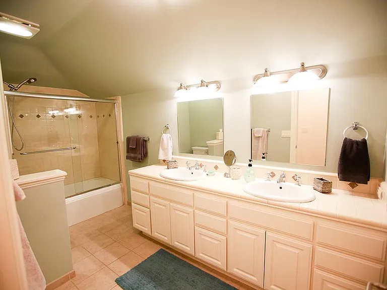 Full upstairs bathroom with shower and bathtub combo, double mirrors, handtowel holders, and matching sinks, plus lots of built-in cabinets and drawers for plenty of space and separation for sharing between the two upstairs bedrooms. Note the low wall sep