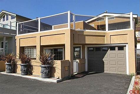 Front of home including courtyard entry, upstairs wrap aroundview deck and garage.