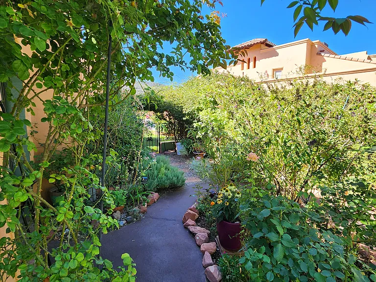 The backyard is a delightful, walled garden full of flowering plants, and provides both a covered sitting area and lovely strolling path.