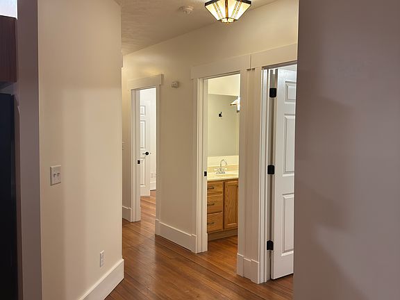 Hallway from kitchen/dining space to bedrooms, bathroom, and entrance
