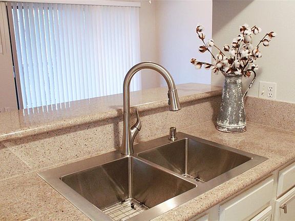 Now that's a sink! It's stainless to coordinate with the other kitchen appliances and there's a view into the living room. The open concept living area and ample window lend to a light an bright atmosphere.