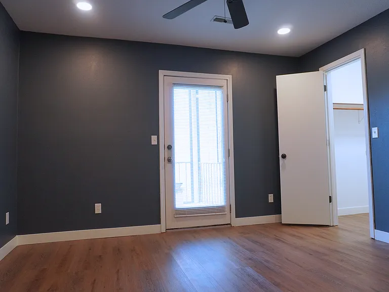 Bedroom 2 featuring a spacious walk-in closet and a walk-out door leading to the screened-in patio_perfect for easy access to outdoor relaxation.